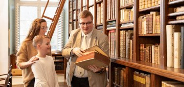Drei Personen bei einer Führung durch die Bibliothek Brehm