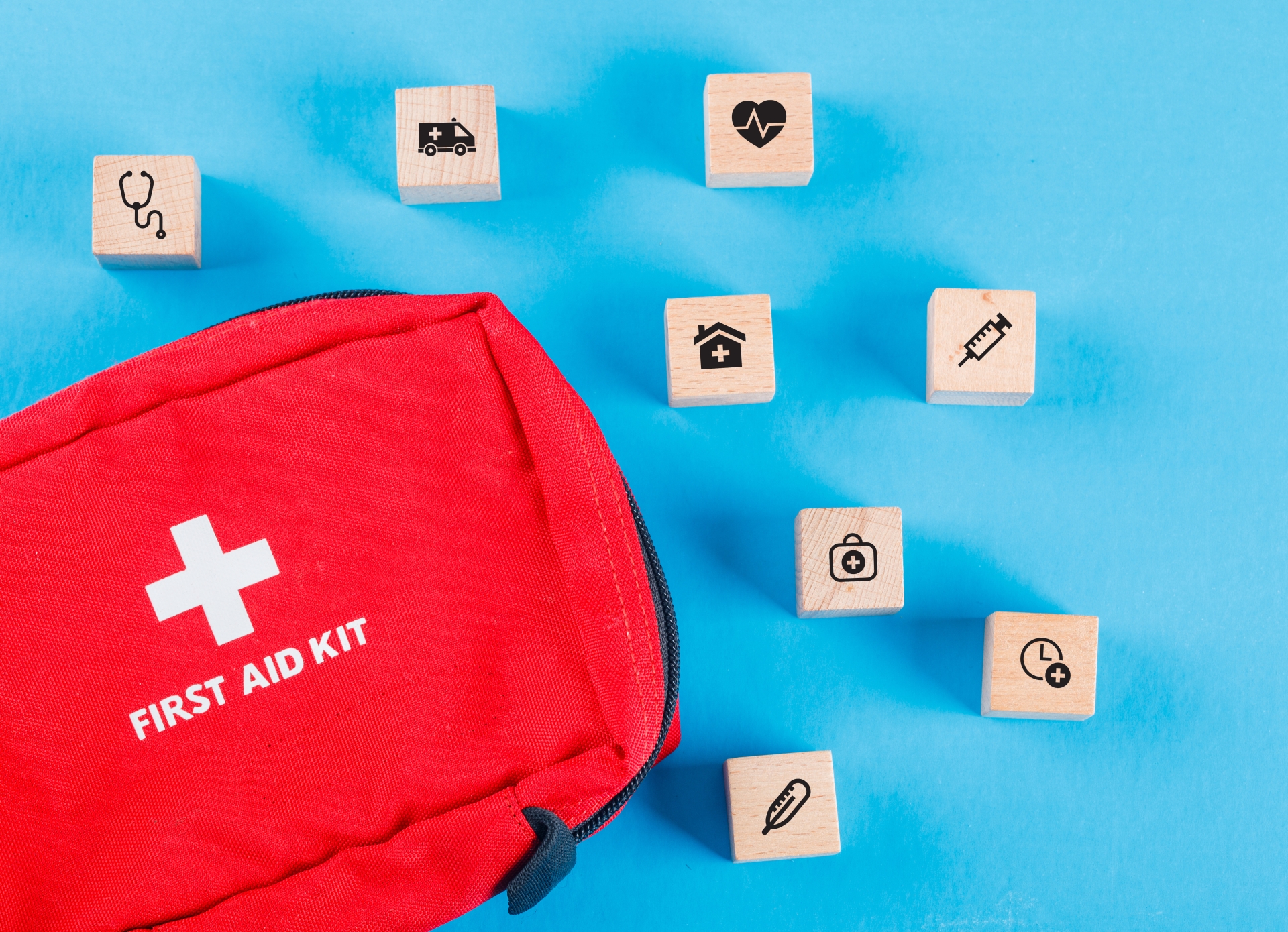 Medical concept with wooden blocks with icons, first aid bag on blue background flat lay. horizontal image Medical concept with wooden blocks with icons, first aid bag on blue background flat lay. horizontal image